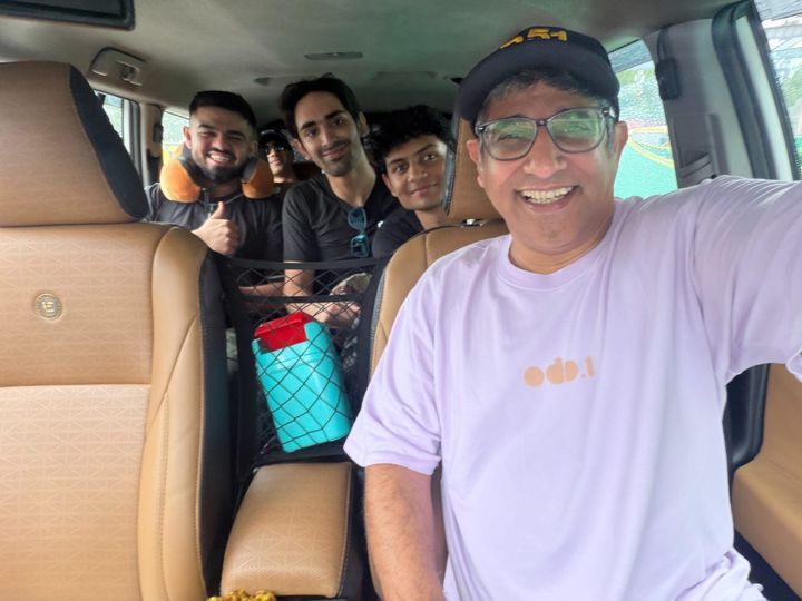A grinning selfie in the front seat, four friends in the rows behind