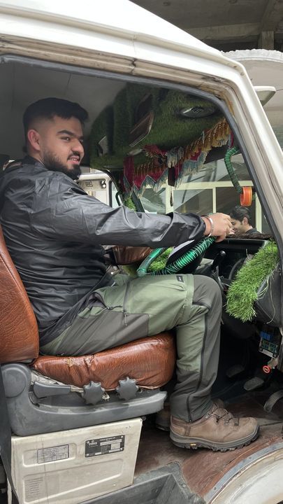 A man in a leather jacket at the wheel of a jeep