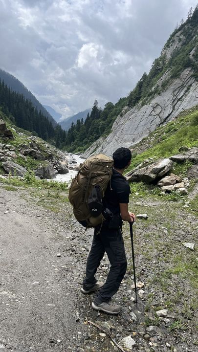 A trekker with a big pack walking up a stony trail