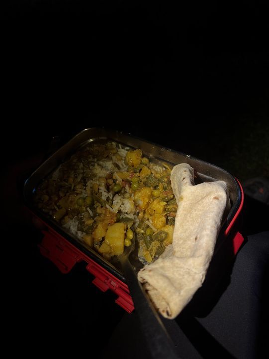 A tin of rice, vegetables and a folded roti by torchlight