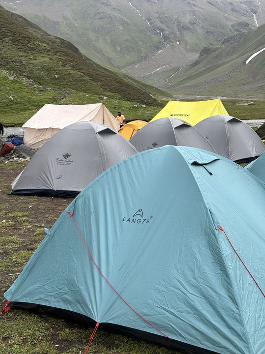 Rows of tents pitched on a meadow beside a stream