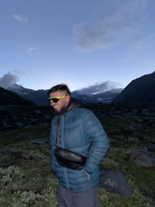A friend in a blue down jacket laughing at dusk below the peaks