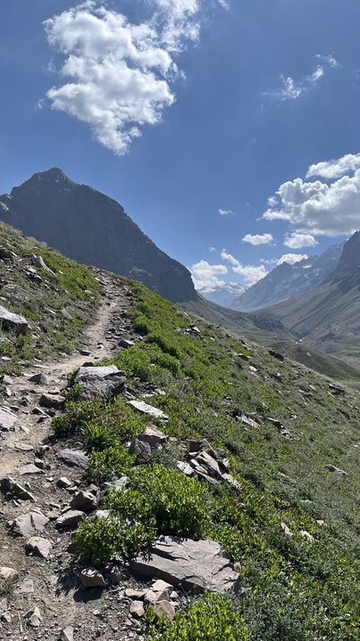 A narrow path winding down a stony slope under blue sky